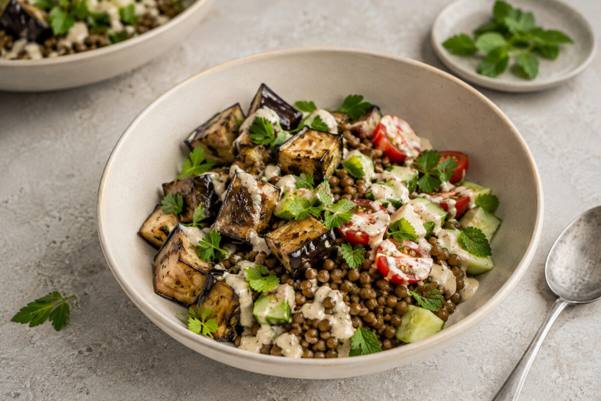 Servier- und Detailansicht der fertigen Auberginen-Linsen-Bowl mit Tahini.
