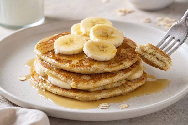 Servierszene mit dem fertigen Gericht. Rezept: Bananen-Hafer-Pancakes mit Ahornsirup
