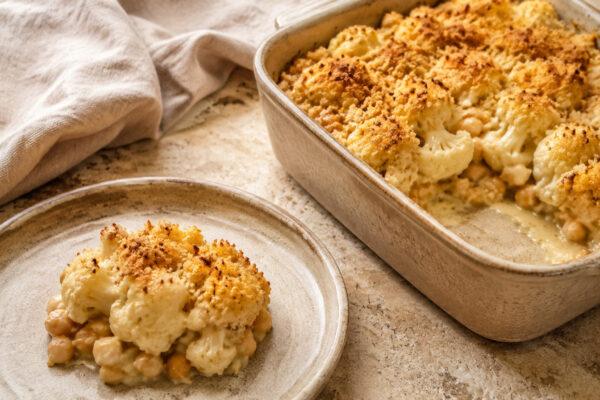 Servierszene mit dem fertigen Gericht. Rezept: Blumenkohl-Kichererbsen-Auflauf mit Tahini-Kruste
