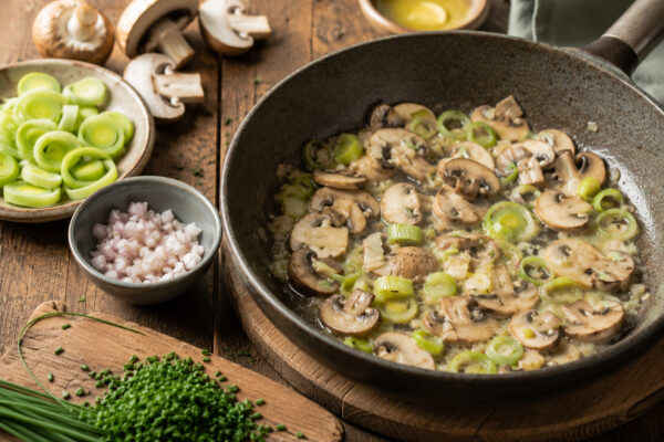 Zutaten- und Vorbereitungsansicht mit Champignons, Lauch, Schalotte und Schnittlauch für die Suppe.