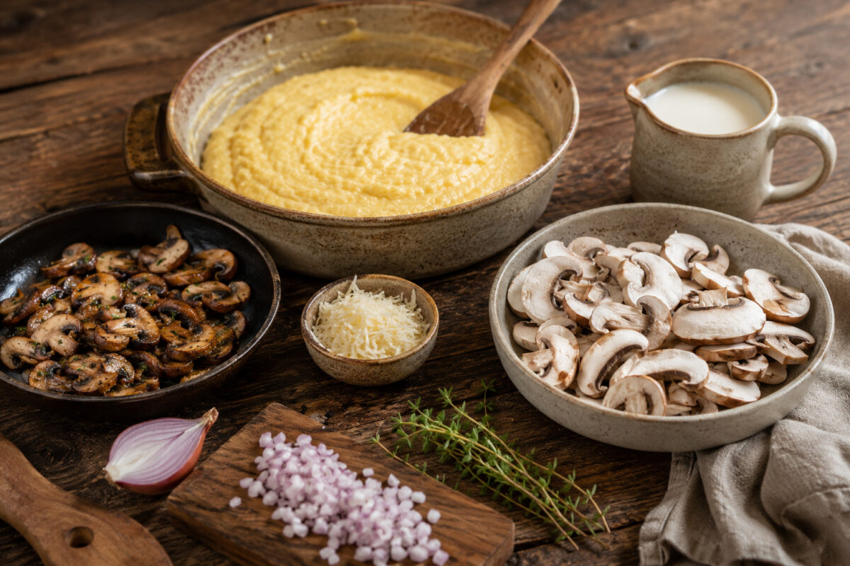 Zutaten- und Vorbereitungsansicht mit Polenta, Pilzen, Schalotte, Thymian, Käse und Milch.