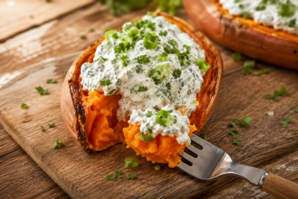 Servier- und Detailansicht einer gefüllten Süßkartoffel mit Kräuterquark und einer Portion auf der Gabel.