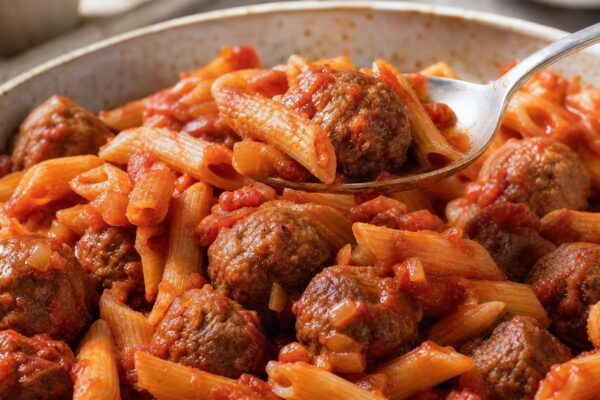Servierszene mit dem fertigen Gericht. Rezept: Hackbällchen in Tomatensauce mit Pasta