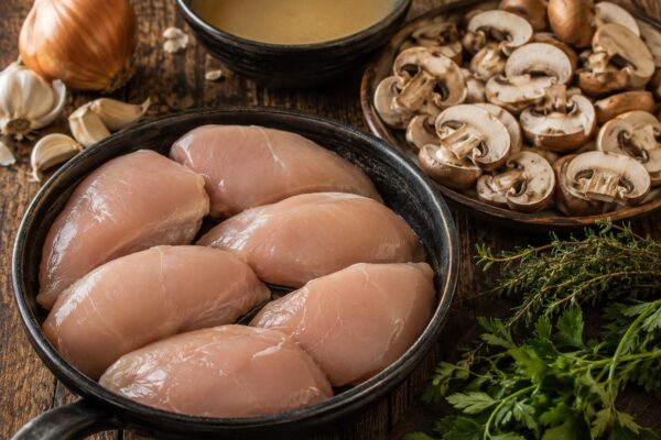 Zutaten- oder Vorbereitungsansicht mit Hähnchen, Champignons und Kräutern.