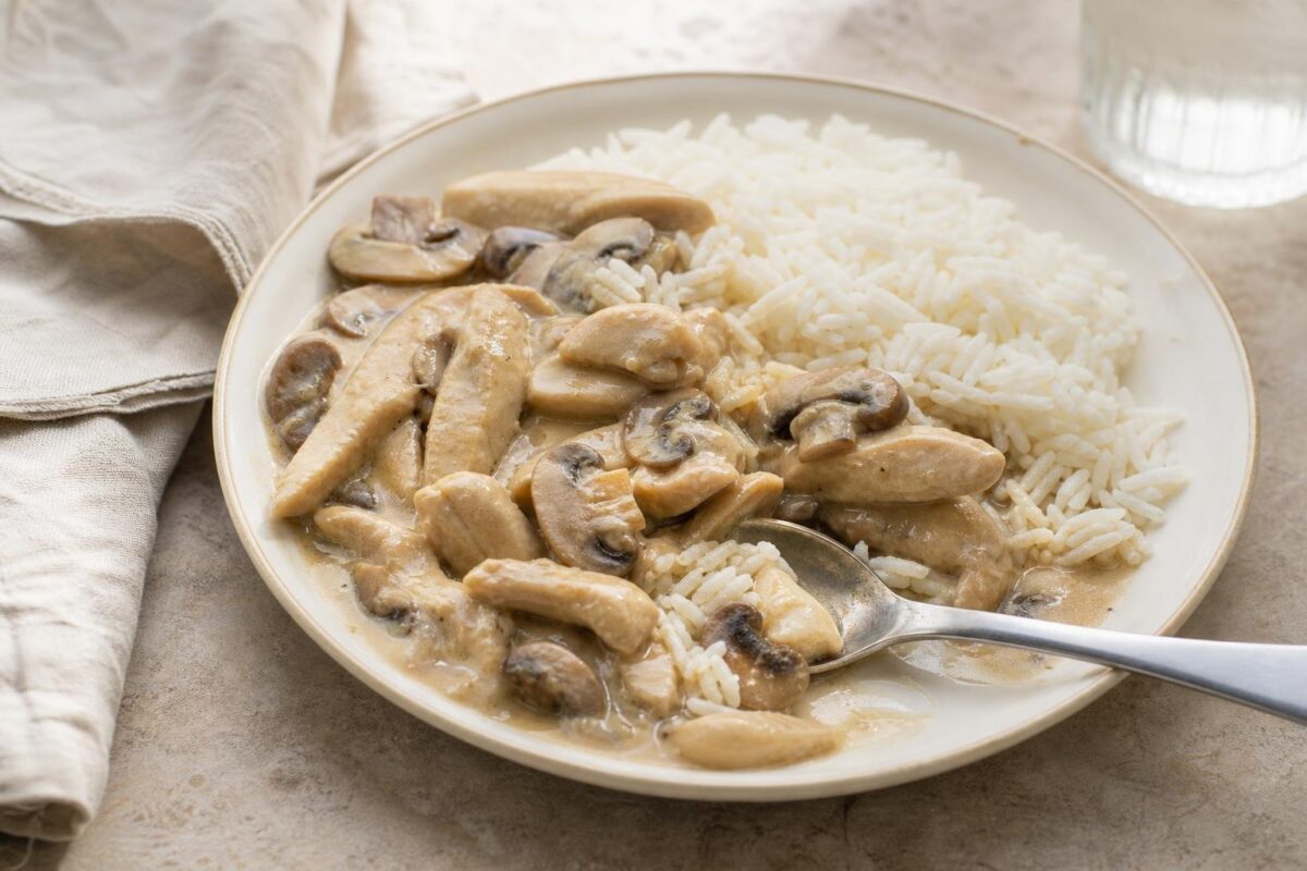 Servierszene mit dem fertigen Gericht. Rezept: Hähnchengeschnetzeltes mit Champignons und Reis