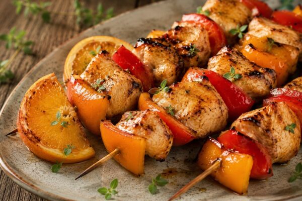 Fertige Hähnchenspieße mit Orange und Paprika als alternative Servier- oder Detailszene.