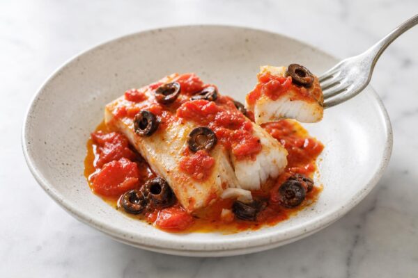 Servierszene mit dem fertigen Gericht. Rezept: Kabeljau mit Tomaten-Oliven-Sauce