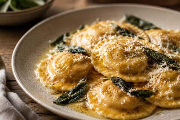 Nahe Servieransicht der fertigen Kürbis-Ricotta-Ravioli mit Salbeibutter und Parmesan.