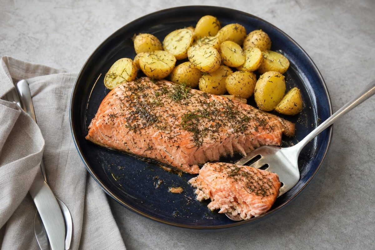 Servierszene mit dem fertigen Gericht. Rezept: Lachs aus dem Ofen mit Kräuterkartoffeln