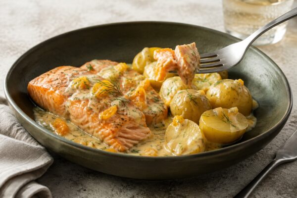 Servierszene mit dem fertigen Gericht. Rezept: Lachs mit Orangen-Dill-Sauce und Kartoffeln