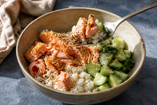 Servierszene mit dem fertigen Gericht. Rezept: Lachs-Reis-Bowl mit Gurke und Sesam