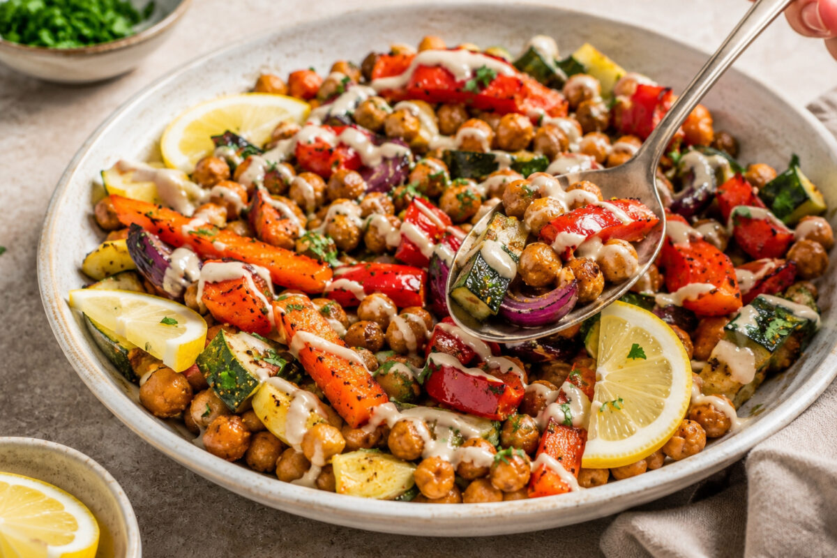 Servierszene mit einer aufgenommenen Portion des fertigen Ofengemüses mit Kichererbsen und Zitronen-Tahini.