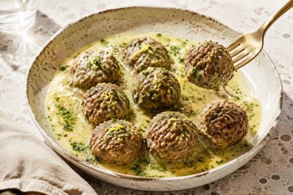 Servierszene mit dem fertigen Gericht. Rezept: Rinderbällchen mit Zitronen-Kräuter-Sauce