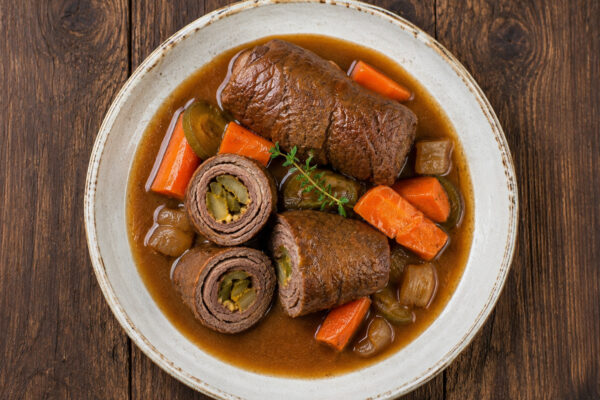 Fertige Rinderrouladen mit Gurken-Senf-Füllung in Bratensauce mit Schmorgemüse.