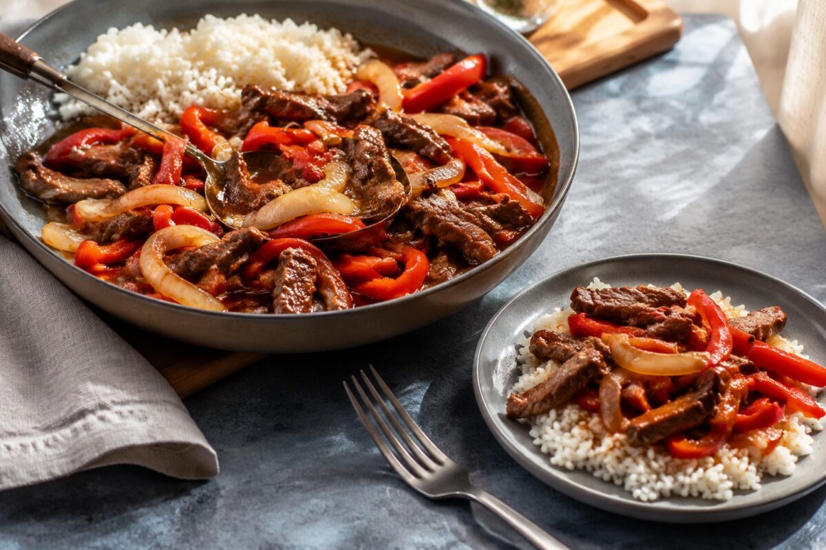 Servierszene mit dem fertigen Gericht. Rezept: Rinderstreifen mit Paprika, Zwiebeln und Reis