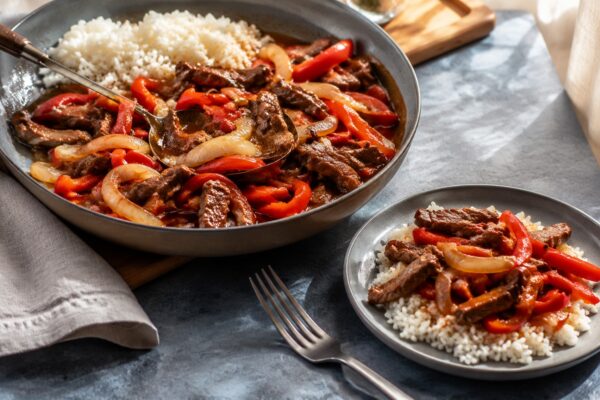Servierszene mit dem fertigen Gericht. Rezept: Rinderstreifen mit Paprika, Zwiebeln und Reis