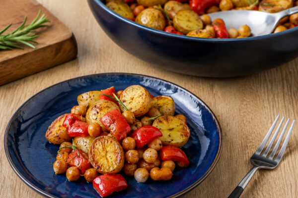 Servierszene mit dem fertigen Gericht. Rezept: Rosmarin-Kartoffeln mit Kichererbsen und Paprika