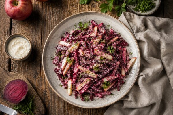 Draufsicht auf den fertigen Rote-Bete-Apfel-Salat mit Meerrettich in heller Schale, cremig gebunden und mit Kräutern bestreut.
