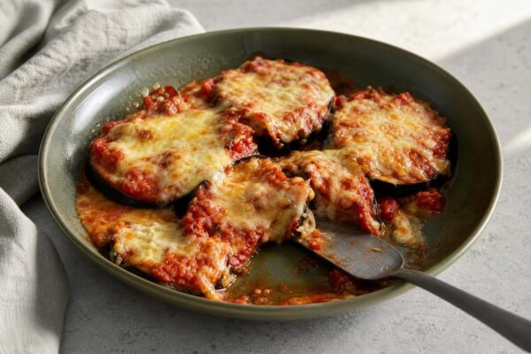 Servierszene mit dem fertigen Gericht. Rezept: Überbackene Auberginen mit Tomatensauce