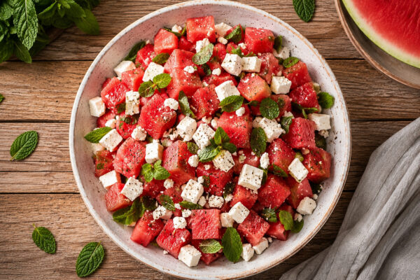 Draufsicht auf den fertigen Wassermelonen-Feta-Salat mit Minze in einer flachen hellen Schale.