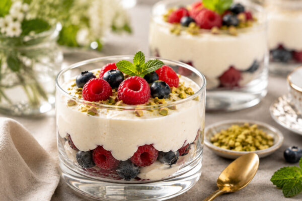 Servierszene mit dem fertigen Gericht. Rezept: Zitronen-Kokos-Creme mit Beeren und Pistazien