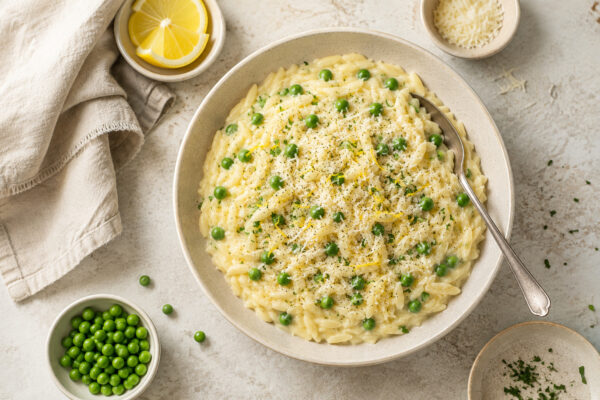 Fertiger Zitronen-Orzo mit Erbsen und Parmesan aus einer deutlich anderen, stärker von oben aufgenommenen Perspektive.